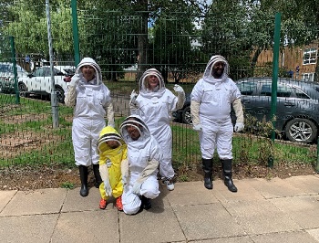 Sustainability committee members pose for photograph wearing beekeeping outfits